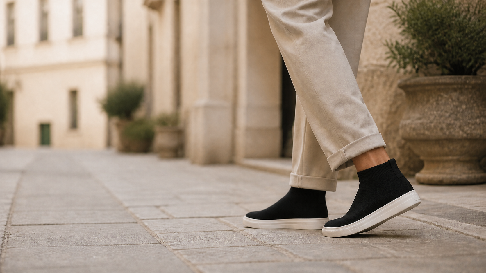 Eine Person trägt schwarze SOMID Daily Sockenschuhe in einer europäischen Altstadt